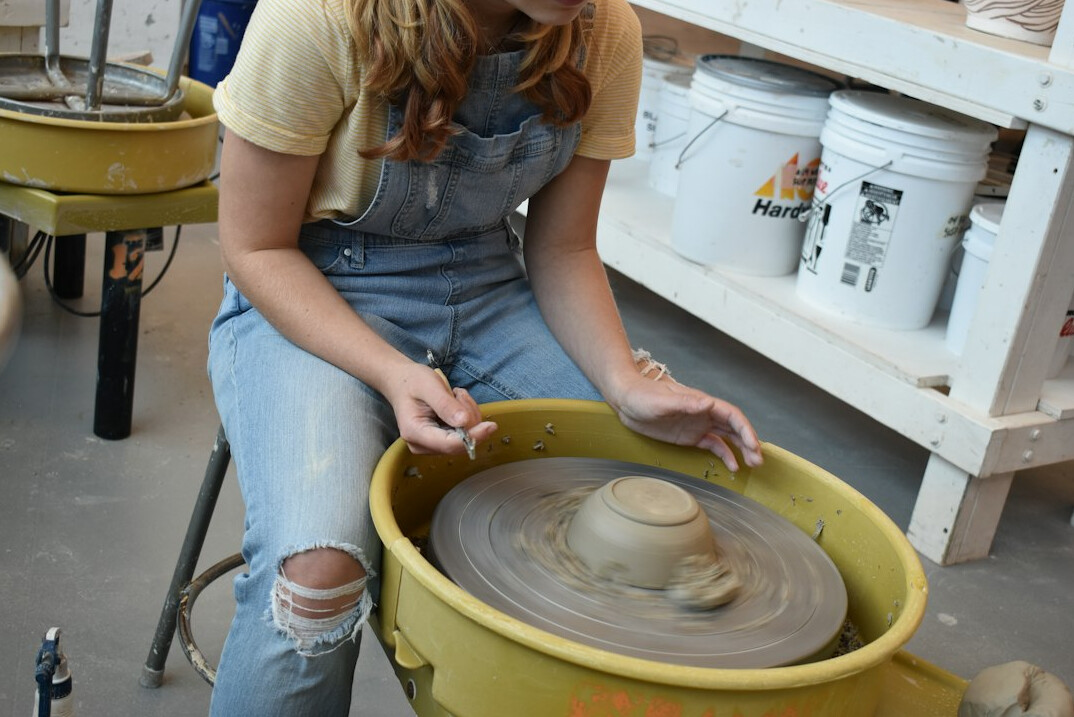 woman shaping clay on pottery wheel